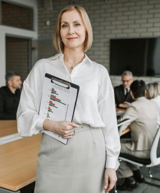 Professional businesswoman holding a clipboard during an office meeting, showcasing leadership in a corporate environment.